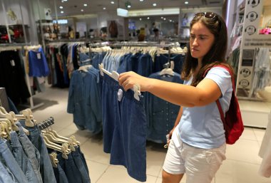 Enflasyona, ekonomik krize, artan fiyatlara ve yaşam giderlerine rağmen bir alışveriş merkezinde mavi ile ilgilenen bir kadın müşteri