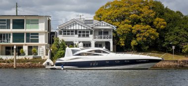 Brisbane, Queensland, Avustralya - Ağustos 2022: Brisbane Nehri kıyısındaki evlerin önüne demirlemiş lüks bir sürat teknesi.