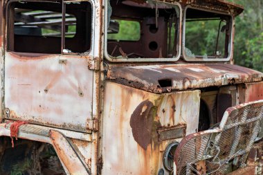 Bu terk edilmiş araç, bakımsız bir dış mekanda kırık pencereler ve paslanmış paneller içeriyor..