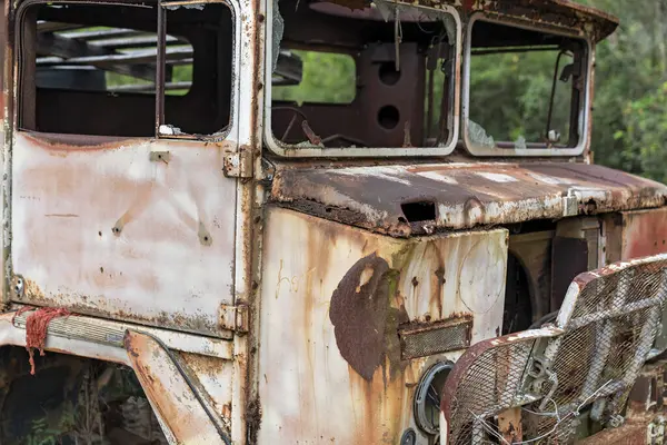 Bu terk edilmiş araç, bakımsız bir dış mekanda kırık pencereler ve paslanmış paneller içeriyor..