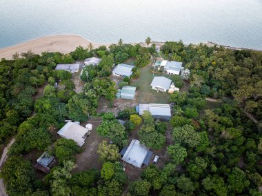 Teneke çatılı evleri, kumlu plajı ve yoğun tropikal yeşilliği olan bir yerleşim yeri..
