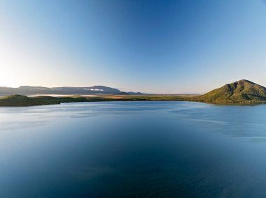 Sağdaki dağ, sabah ışığında mavi körfezde gölgeler oluşturur..