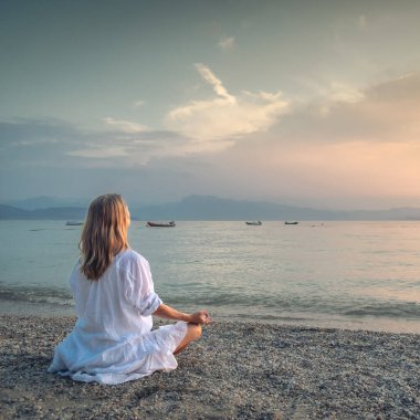 Woman meditating at the Garda Lake. Yoga practice. Sunset. Italy