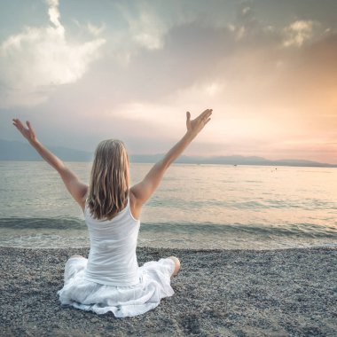 Woman meditating at the Garda Lake. Yoga practice. Sunset. Italy