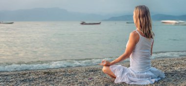 Woman meditating at the Garda Lake. Yoga practice. Sunset. Italy