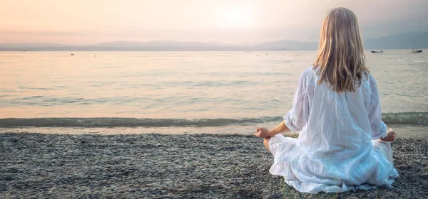 Woman meditating at the Garda Lake. Yoga practice. Sunset. Italy