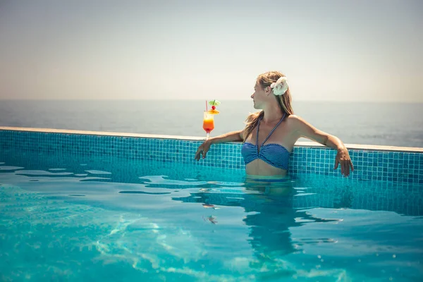 女人放松与鸡尾酒游泳池 — 图库照片