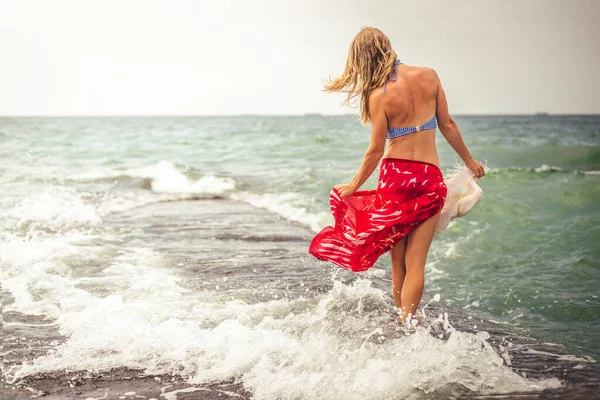 美丽的女人走在海的那边穿红色连衣裙 — 图库照片