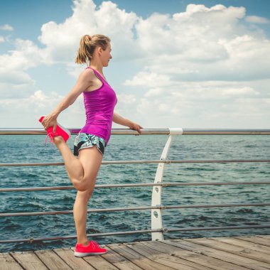 Genç güzel sportif kız sahil üzerinde çalıştırmak için hazırlanma.