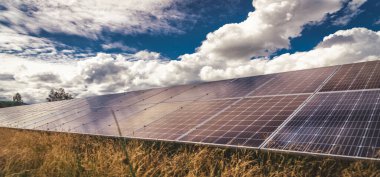 Solar panels and blue sky with clouds and green grass