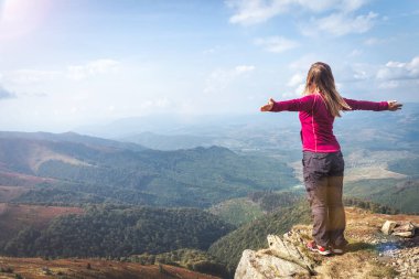 Sırt çantalı genç bir kadın dağda yürüyüş yapıyor.