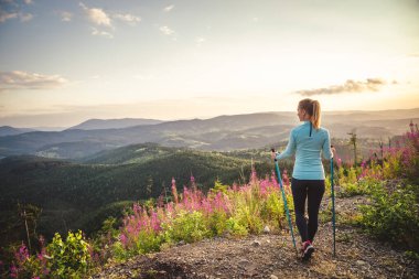 Sırt çantalı genç bir kadın dağda yürüyüş yapıyor.