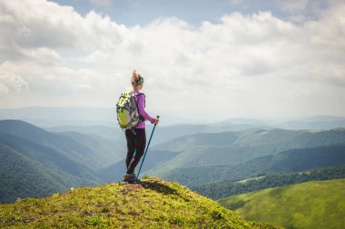 Sırt çantalı genç bir kadın dağda yürüyüş yapıyor.