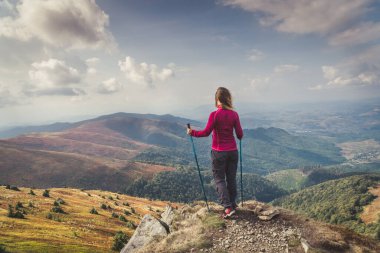 Sırt çantalı genç bir kadın dağda yürüyüş yapıyor.