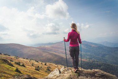Sırt çantalı genç bir kadın dağda yürüyüş yapıyor.