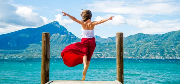 Vrouw Rode Jurk Springt Bij Het Gardameer Italië — Stockfoto