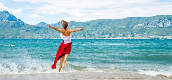 身穿红色衣服的女人跳到加尔达湖边 意大利 — 图库照片