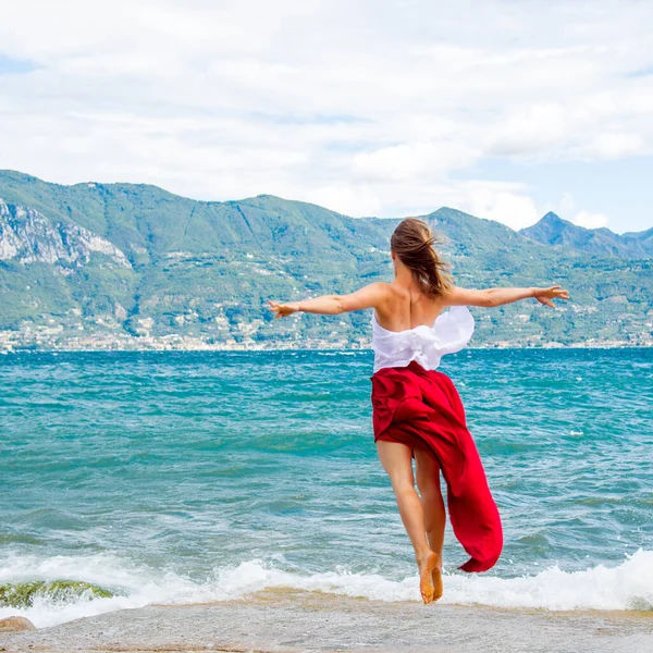 Vrouw Rode Jurk Springt Bij Het Gardameer Italië — Stockfoto