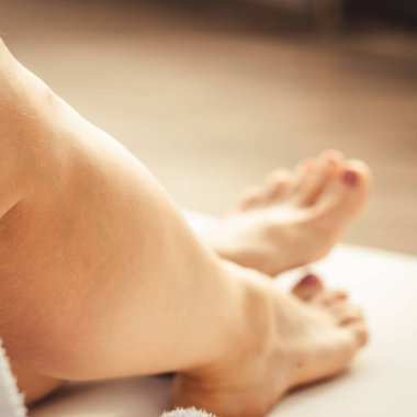Womans feet in white bathrobe lying on sofa and relaxing at the roof at hotel