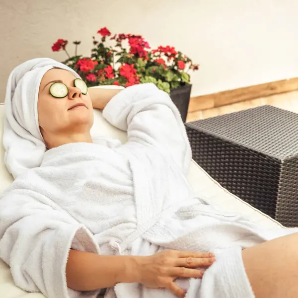 stock image Relaxed young woman getting eye nature treatment by cucumber at luxury spa resort. Wellness and healing concept.