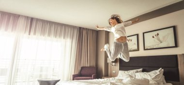 güzel kadın eğlenmek ve otel odasında yatakta bornoz ile atlama