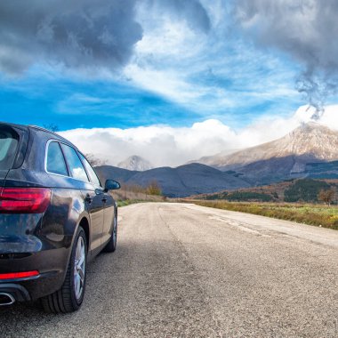 Dağ yolunda seyahat etmek için bir araba. Mavi gökyüzü