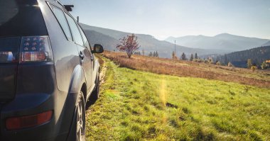 Dağ yolunda seyahat etmek için bir araba. Mavi gökyüzü ve güneş