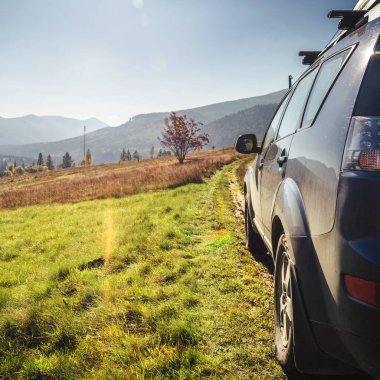 Dağ yolunda seyahat etmek için bir araba. Mavi gökyüzü ve güneş