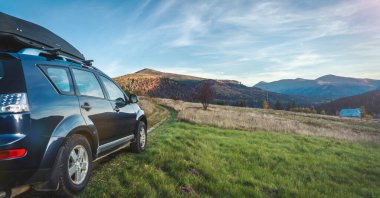 Dağ yolunda seyahat etmek için bir araba. Mavi gökyüzü ve güneş