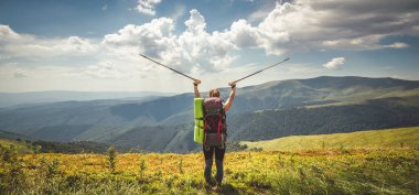 Sırt çantalı genç bir kadın dağda yürüyüş yapıyor.