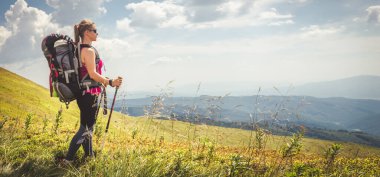 Sırt çantalı genç bir kadın dağda yürüyüş yapıyor.