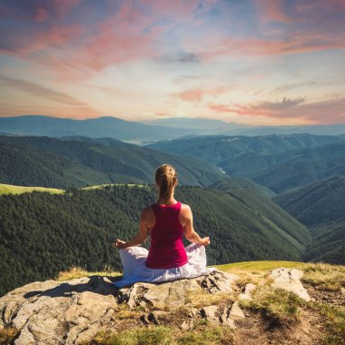 Genç bir kadın dağın tepesinde meditasyon yapıyor. Dramatik gökyüzü