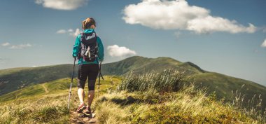 Sırt çantalı genç bir kadın dağda yürüyüş yapıyor.