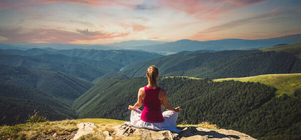 Young woman meditate on the top of mountain. Dramatic sky