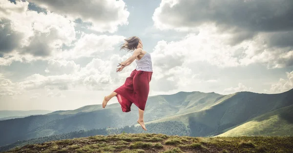 Junge Frau Springt Auf Den Gipfel Der Berge lizenzfreie Stockfotos