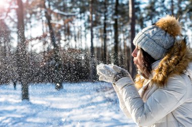 Beyaz şapkalı kız Ormanda kar üflüyor Güneşli bir günde.