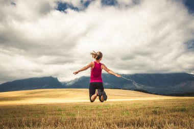 Sırt çantasız genç bir kadın dağlarda yürüyüş yapıyor. Alpler