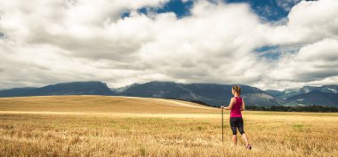 Sırt çantasız genç bir kadın dağlarda yürüyüş yapıyor. Alpler