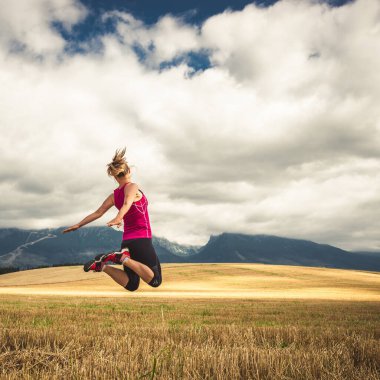 Sırt çantasız genç bir kadın dağlarda yürüyüş yapıyor. Alpler