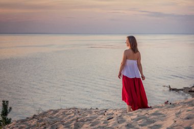 Kırmızı elbiseli kadın denizde pratik yapıyor. günbatımı