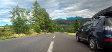 car for traveling with a mountain road. Dramatic sky
