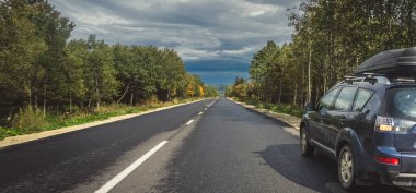 car for traveling with a mountain road. Dramatic sky