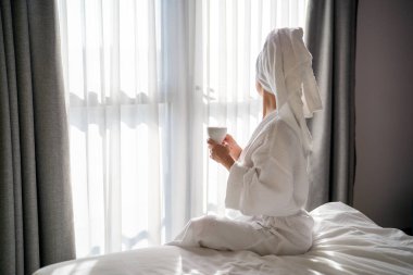 Sabahları bornozlu bir kadın ve bir fincan kahve.