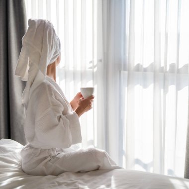 Sabahları bornozlu bir kadın ve bir fincan kahve.