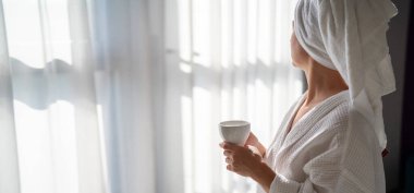 Sabahları bornozlu bir kadın ve bir fincan kahve.