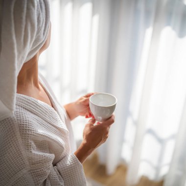 Sabahları bornozlu bir kadın ve bir fincan kahve.