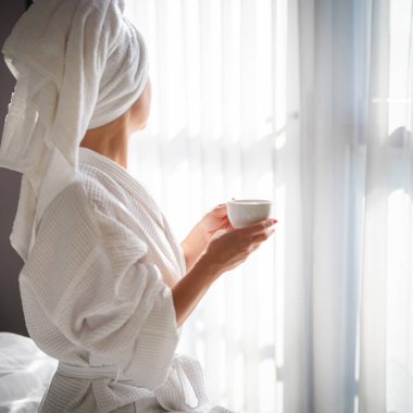 Sabahları bornozlu bir kadın ve bir fincan kahve.