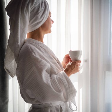 Sabahları bornozlu bir kadın ve bir fincan kahve.