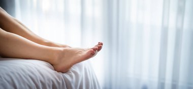 Yatağın üzerinde genç bir kadının bacaklarının yakın çekimi. Otel