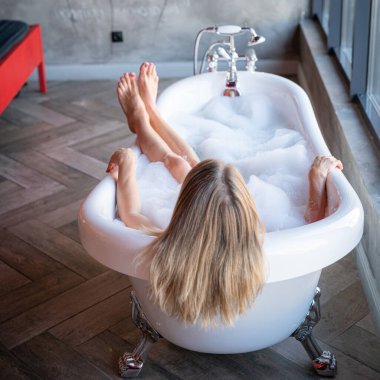 Kadın ayakları otel odasında bornozla rahatlar, yakın plan.